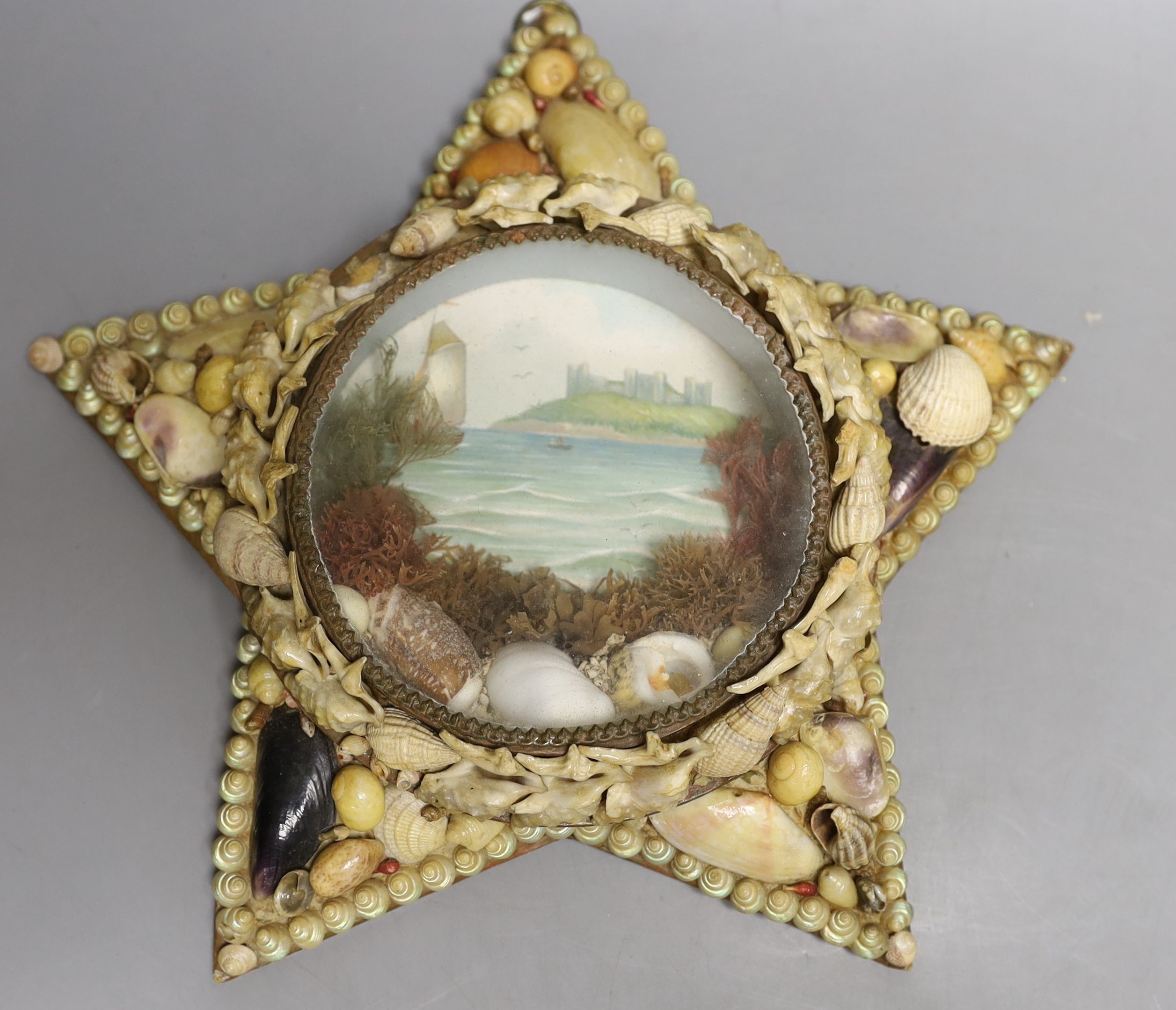 A shell mounted star with central scenic seascape and a shell hand mirror, star 24 cms wide.